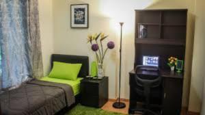 a room with a bed and a desk with a green couch at Staff Guest House in Nyíregyháza