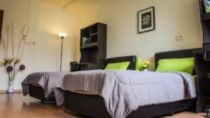 a bedroom with a large bed with green pillows at Staff Guest House in Nyíregyháza +1 photo