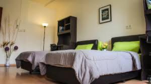 1 dormitorio con 1 cama grande con almohadas verdes en Worker's Apartman-Munkásszálló, en Igricetanya