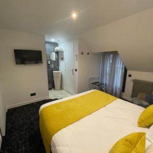 Cette chambre d'hôtel comprend un lit avec une couverture jaune. dans l'établissement Le Sainte Jeanne, à Cormeilles-en-Vexin