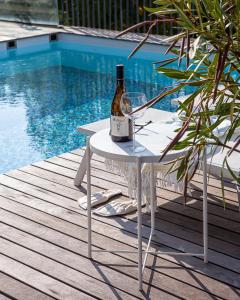 Una botella de vino sentada en una mesa junto a una piscina en Villa Alma Vista, en Dobrovo