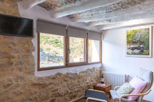 uma sala de estar com uma parede de pedra e uma televisão em La LUNA Casa rural Vall de Gallinera refugio em Patró