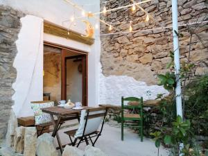 un patio con mesa, sillas y pared de piedra. en La LUNA Casa rural Vall de Gallinera refugio, en Patró