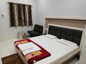 ein Schlafzimmer mit einem großen Bett und einem Stuhl in der Unterkunft HOTEL SHANTIDOOT , Gadarwara in Gādarwāra