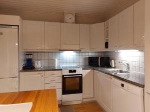 a white kitchen with white cabinets and a sink at Tupasvilla in Syöte