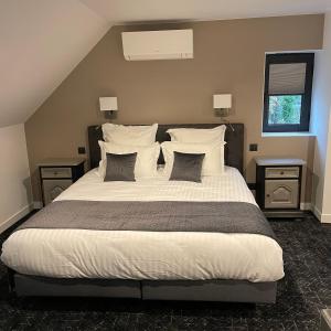 een slaapkamer met een groot bed met witte lakens en kussens bij Le Sainte Jeanne in Cormeilles-en-Vexin