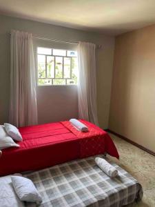 Cama roja en habitación con ventana en Residencial Vista da Serra, en Diamantina