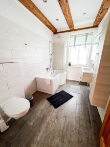 ein Badezimmer mit einer Badewanne, einem WC und einem Waschbecken in der Unterkunft FerienGut Gaarz - Cottage 29 in Göhl
