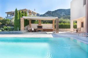 a swimming pool in front of a house at Vlasis' Eden Villa in Sálakos