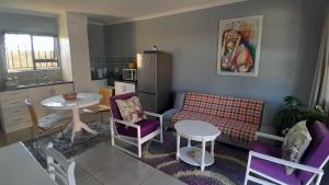 ein Wohnzimmer mit einem Tisch und einem Sofa sowie eine Küche in der Unterkunft Be-My-Guest Holiday Apartment in Maseru