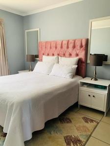 um quarto com uma cama grande e uma cabeceira rosa em Be-My-Guest Holiday Apartment em Maseru