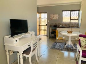 ein Wohnzimmer mit einem weißen Tisch und einem TV in der Unterkunft Be-My-Guest Holiday Apartment in Maseru