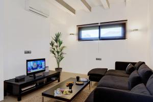 een woonkamer met een bank en een tv bij Villa Marcelino in Port de Pollença