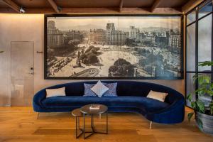 a blue couch in a living room with a painting at Hotel Paxton Barcelona in Barcelona