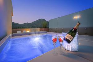 eine Flasche Champagner und zwei Gläser neben dem Pool in der Unterkunft Penthouse Dalias in Port de Pollença