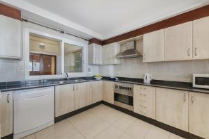 een keuken met witte apparaten en houten kasten bij Apartment VistaMar I in Port de Pollença