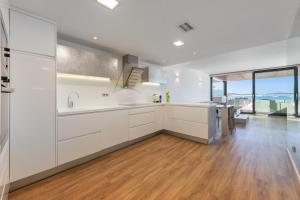 a kitchen with white cabinets and a wooden floor at Londres Derecha in Port de Pollensa