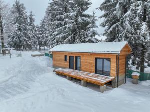 una pequeña cabaña en la nieve con un banco en black well, en Jablonec nad Nisou