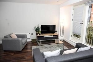 OnPoint - Spacious 2 Bedroom Apt, City Centre! في مانشستر: غرفة معيشة مع أريكة وتلفزيون
