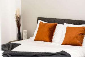 a bed with orange and white pillows on it at OnPoint - Spacious 2 Bedroom Apt, City Centre! in Manchester