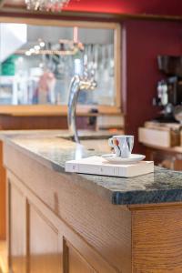 a book sitting on a counter with a coffee cup at Hotel L'Abri in Le Puy-en-Velay