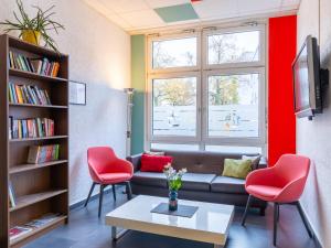 salon z kanapą i 2 czerwonymi krzesłami w obiekcie Good Morning Berlin City West w Berlinie