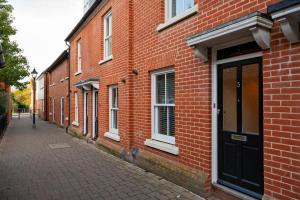 a brick building with a black door on a street at The Copperfield - Modern 4 Bed house with parking in Canterbury