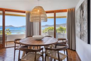 een eetkamer met een tafel en stoelen en uitzicht op de oceaan bij El Faro in Port de Pollença
