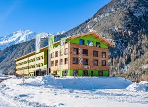 a hotel with snow in front of a mountain at Explorer Hotel Ötztal in Umhausen