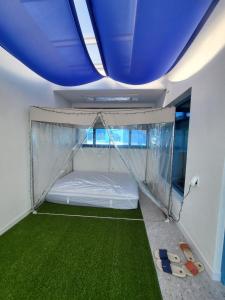 een slaapkamer met een bed in een tent met een groene vloer bij Yeosu Blueara Premium Pool Villa in Yeosu