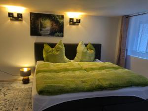 a bedroom with a bed with a green blanket and pillows at Sweet Ferienwohnung Bayreuth City in Bayreuth