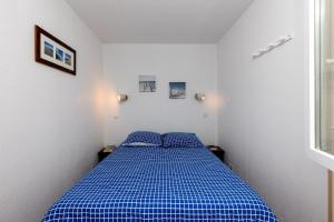 Cama azul en habitación blanca con 2 almohadas azules en Blue Pinsolle - Appt avec piscine partagée, en Soustons