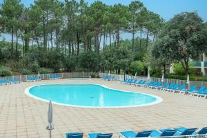una piscina con tumbonas azules y árboles en Blue Pinsolle - Appt avec piscine partagée, en Soustons
