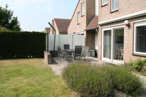 a patio with chairs and a table in front of a house at Crox Houcke 65 in Nieuwvliet