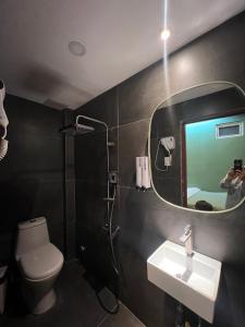 a person taking a picture of a bathroom with a mirror at Meow Hotel & Cafe 2 in Ho Chi Minh City