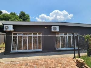 a black house with two windows and air conditioning at WAMPEX GUEST HOUSE IN RUSTENBURG in Rustenburg
