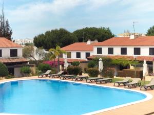 a swimming pool with chaise lounge chairs and a resort at V2 Vilar Jardim Piscina wifi in Quarteira