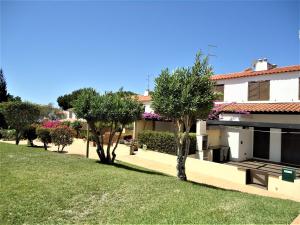 a house with trees and a grass yard at V2 Vilar Jardim Piscina wifi in Quarteira