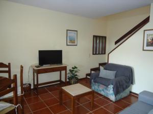 a living room with a tv and a couch and a table at V2 Vilar Jardim Piscina wifi in Quarteira
