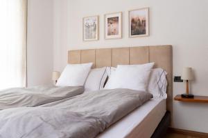 una camera da letto con un grande letto con lenzuola e cuscini bianchi di Chalet Ginepro a Santa Caterina Valfurva