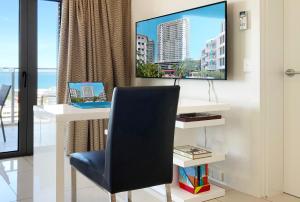 einen Schreibtisch mit Stuhl und einen TV an der Wand in der Unterkunft "PADSTOW" Top Location & Views at PenthousePads in Darwin