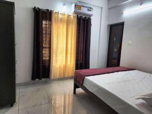 a bedroom with a bed and windows with curtains at GOPURAM in Trivandrum