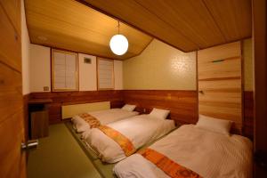 a bedroom with two beds in a room with a door at Raicho Lodge Madarao in Iiyama