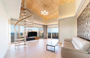 uma sala de estar com uma escada em espiral e um sofá em Geumdanyoung Pension em Jeju