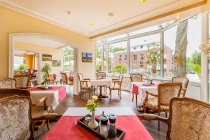 ein Restaurant mit Tischen und Stühlen und einem großen Fenster in der Unterkunft Akzent Hotel Berlin in Bad Bevensen