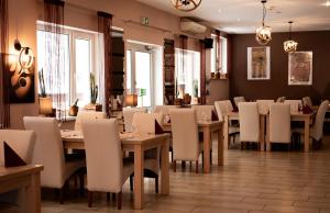 a restaurant with wooden tables and white chairs at High Class Suites Mazuria in Mrągowo