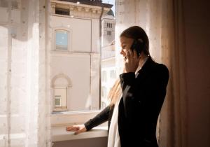 a woman talking on a cell phone in front of a window at Klemi, rooms in old town Dolomia best home Check in automatico in Trento