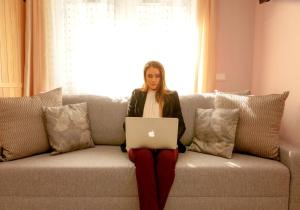 kobieta siedząca na kanapie z laptopem w obiekcie Klemi, rooms in old town Dolomia best home Check in automatico w Trydencie