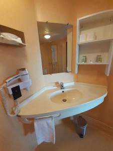 a bathroom with a sink and a mirror at La Villa des Golf.e.s in Theix