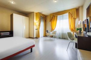 a hotel room with a bed and a desk and chairs at JR Hotels Bologna Amadeus in Bologna